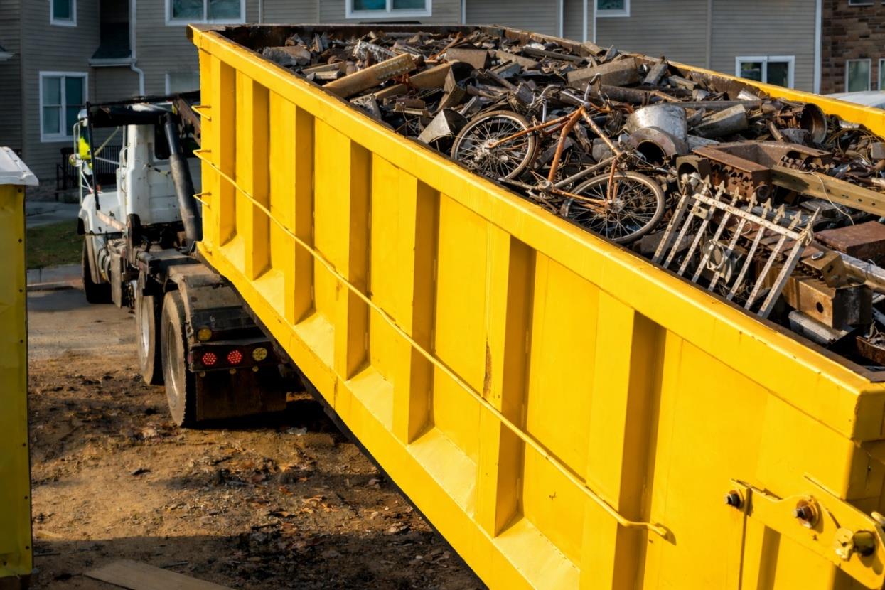 Yellow dumpster filled with metal scrap items.